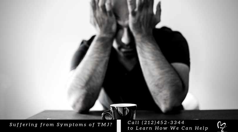 Man holding head in pain with coffee cup on table